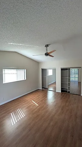 an empty room with windows and ceiling fan