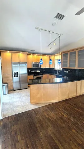 a kitchen with stainless steel appliances granite countertop a stove a sink and a wooden floors