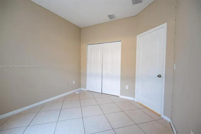 a view of an empty room with closet and a window