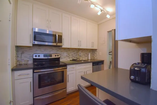 a kitchen with cabinets stainless steel appliances and wooden floor