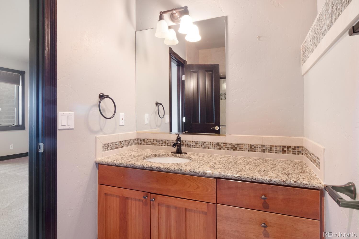 160 Fuller Placer Road Breckenridge, CO 80424 - Photo 38 of 47 a bathroom with a granite countertop sink and a mirror