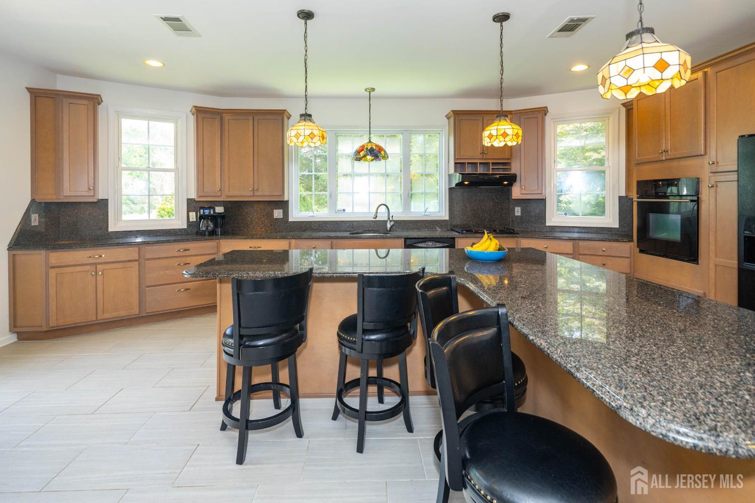 294 Fresh Ponds Road North Brunswick, NJ 08902 - Photo 13 of 53 a kitchen with stainless steel appliances granite countertop a stove a sink a microwave a dining table and chairs with wooden floor
