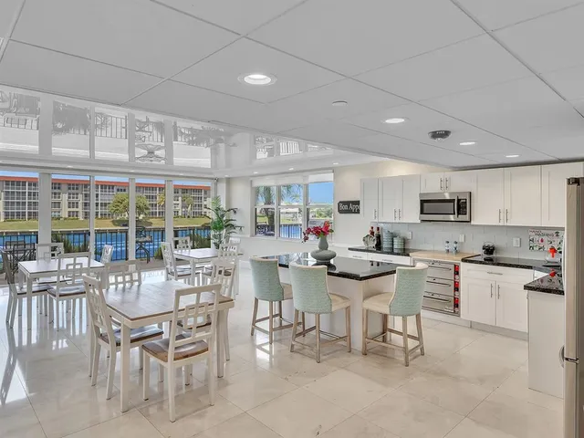 a kitchen with stainless steel appliances a dining table chairs stove and white cabinets