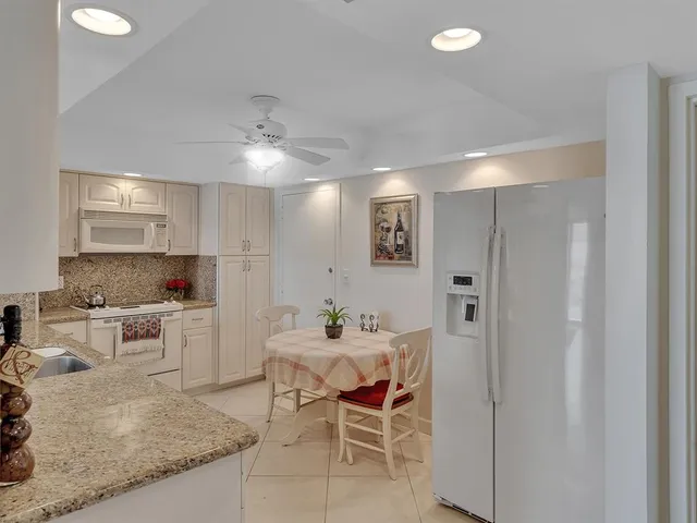 a kitchen with a dining table chairs and white cabinets