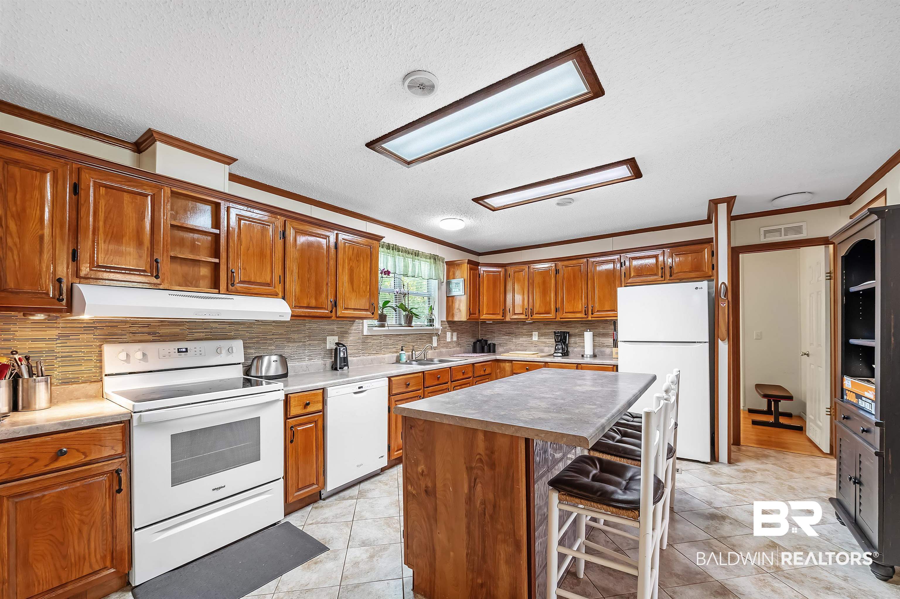 10970 Stucki Road Elberta, AL 36530 - Photo 21 of 56 Kitchen with light tile patterned flooring, a kitchen island, crown molding, and white appliances