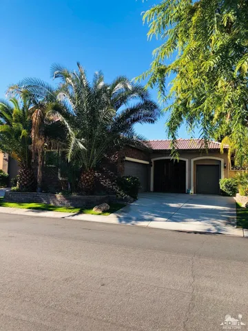 a view of a house with a yard and palm trees