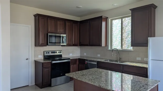 a kitchen with stainless steel appliances granite countertop a stove a sink and a microwave