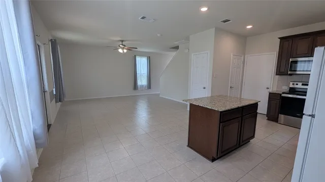 a kitchen with kitchen island granite countertop a refrigerator and a sink