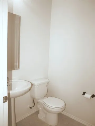 a white toilet sitting next to a white sink and vanity