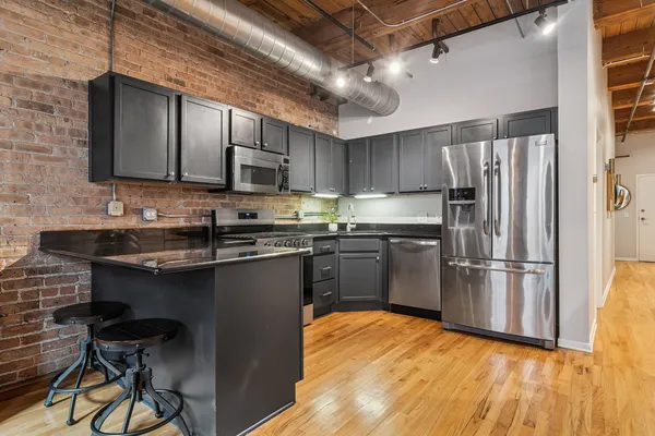 a kitchen with stainless steel appliances granite countertop a refrigerator a sink dishwasher a stove and a microwave oven on dining table