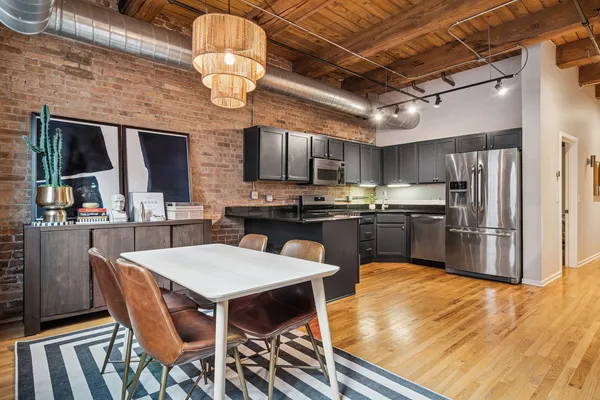 a kitchen with stainless steel appliances granite countertop a table chairs sink refrigerator and microwave