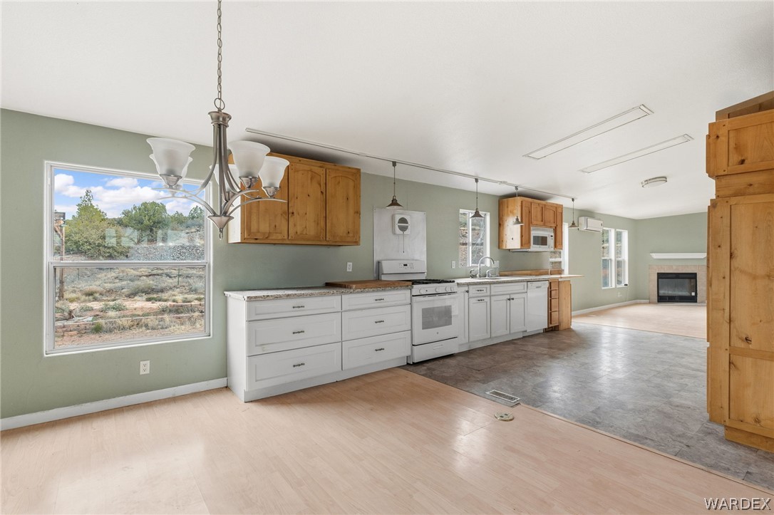3894 North Lookout Canyon Road Kingman, AZ 86401 - Photo 12 of 64 Kitchen with white appliances, hanging lights, a glass covered fireplace, light countertops, and light wood-style flooring