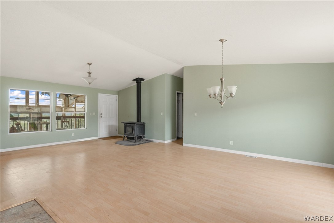3894 North Lookout Canyon Road Kingman, AZ 86401 - Photo 13 of 64 Unfurnished living room with a wood stove, light wood finished floors, suspended lighting, and lofted ceiling