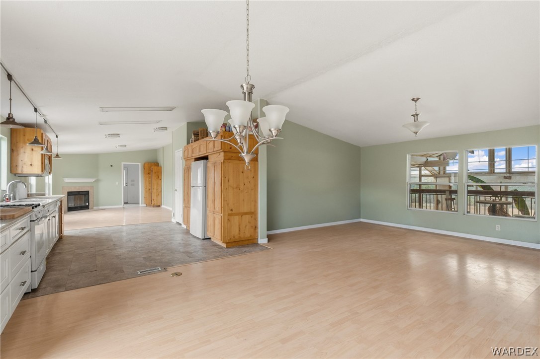 3894 North Lookout Canyon Road Kingman, AZ 86401 - Photo 14 of 64 Unfurnished dining area with a glass covered fireplace, light wood-style floors, hanging lights, and lofted ceiling