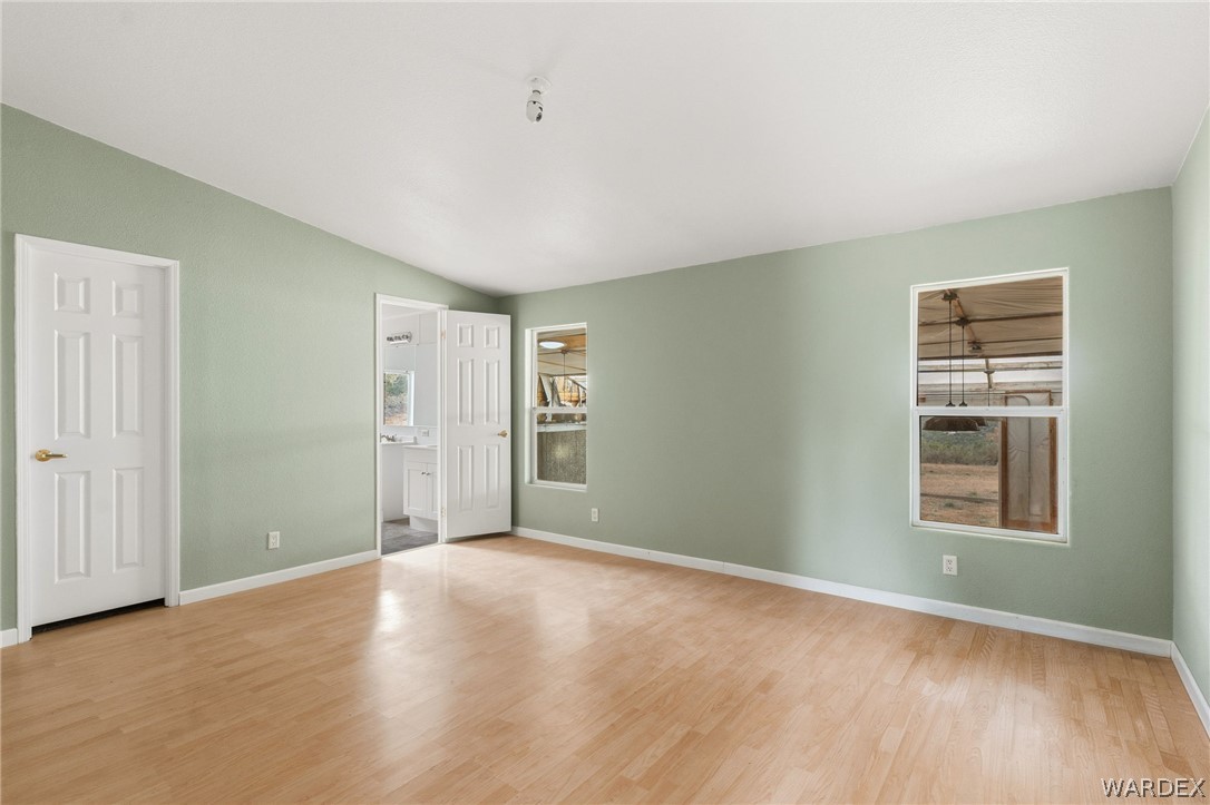 3894 North Lookout Canyon Road Kingman, AZ 86401 - Photo 17 of 64 Unfurnished bedroom with light wood-style floors, lofted ceiling, and ensuite bath