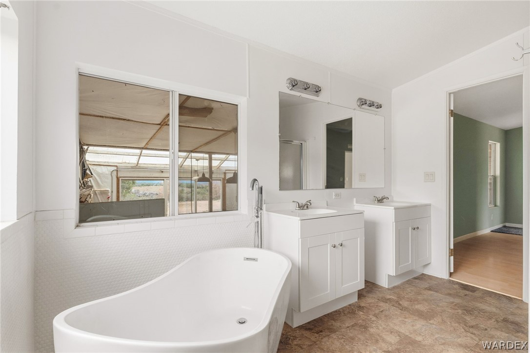 3894 North Lookout Canyon Road Kingman, AZ 86401 - Photo 20 of 64 Bathroom with a freestanding tub, two vanities, and a stall shower