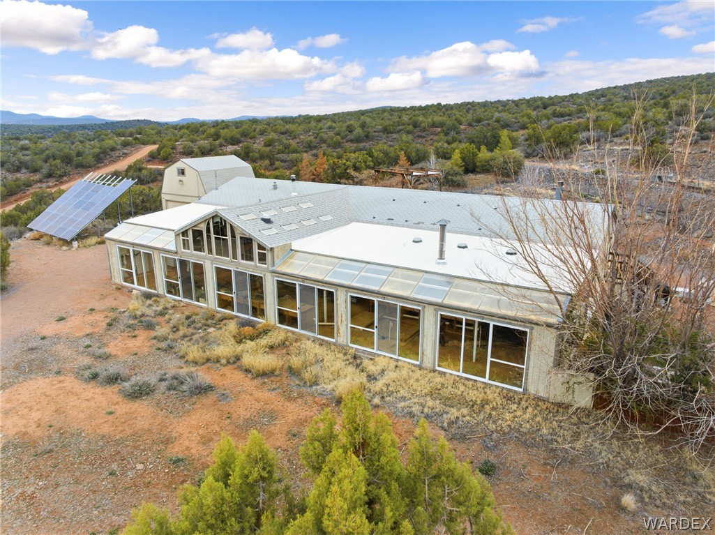 3894 North Lookout Canyon Road Kingman, AZ 86401 - Photo 4 of 64 Rear view of property featuring solar panels, a sunroom, and a view of trees