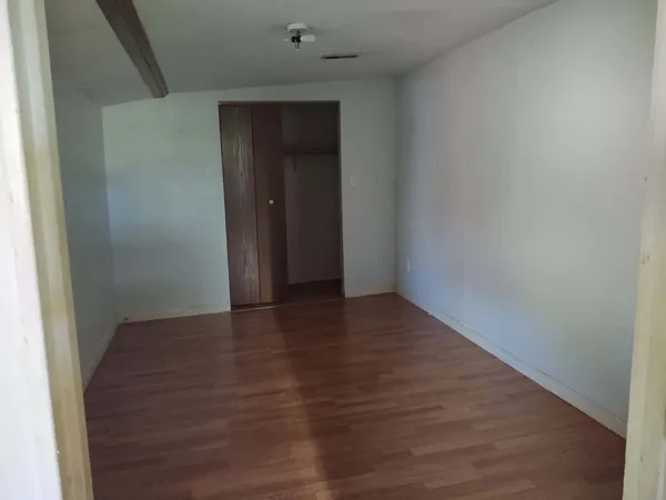 a view of an empty room with wooden floor and closet