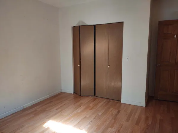 an empty room with wooden floor and closet area
