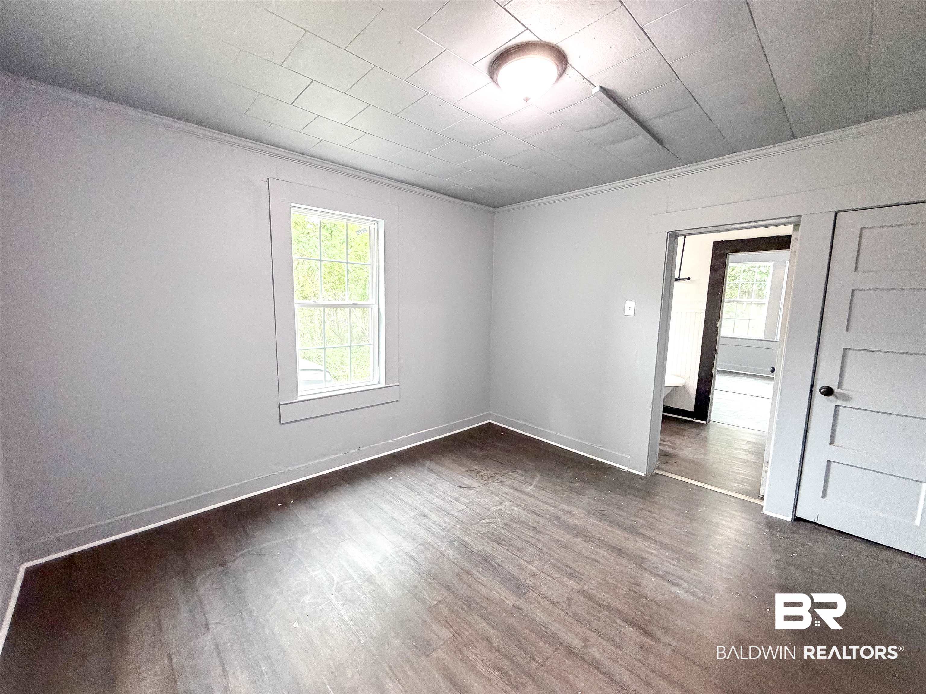 38 Flock Avenue Mobile, AL 36610 - Photo 13 of 27 Room featuring wood-finish flooring, light gray walls, white trim, and a single window with white framing
