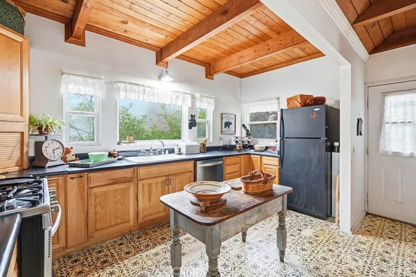 a kitchen with stainless steel appliances granite countertop a refrigerator a sink dishwasher a stove and white countertops with wooden floor