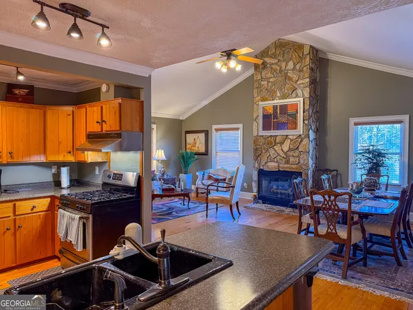 a kitchen with stainless steel appliances granite countertop a sink dishwasher a dining table and chairs with wooden floor