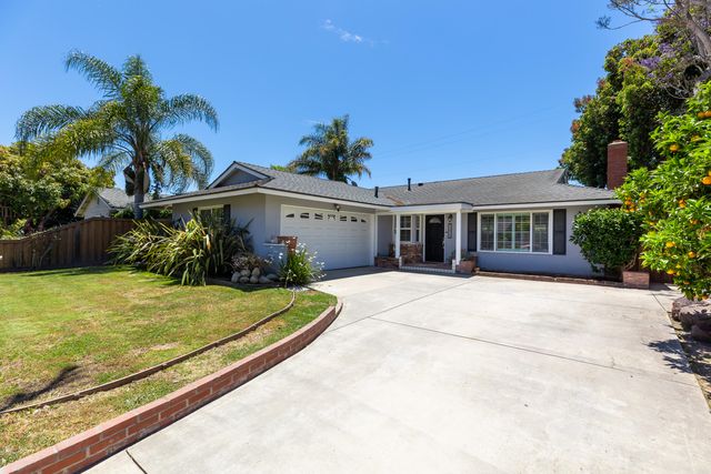 a front view of house with yard and trees in the background