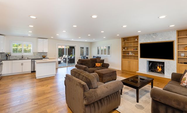 a living room with furniture a fireplace a flat screen tv and kitchen view