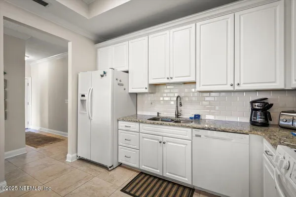 a kitchen with stainless steel appliances granite countertop a refrigerator sink and white cabinets