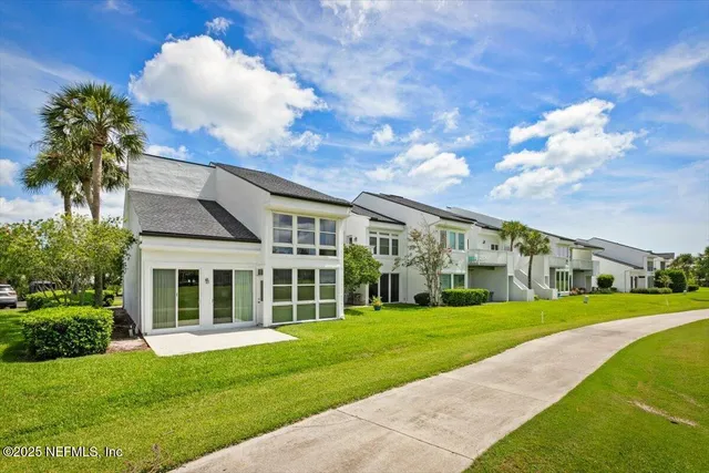 a view of an apartment with a big yard and large trees