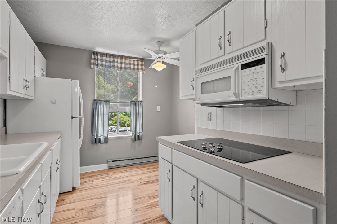 3064 Kent Road, Unit 101 Stow, OH 44224 - Photo 18 of 40 Kitchen featuring light wood-finish flooring, white cabinetry, integrated white appliances, a smooth-surface electric cooktop, and a white tile backsplash