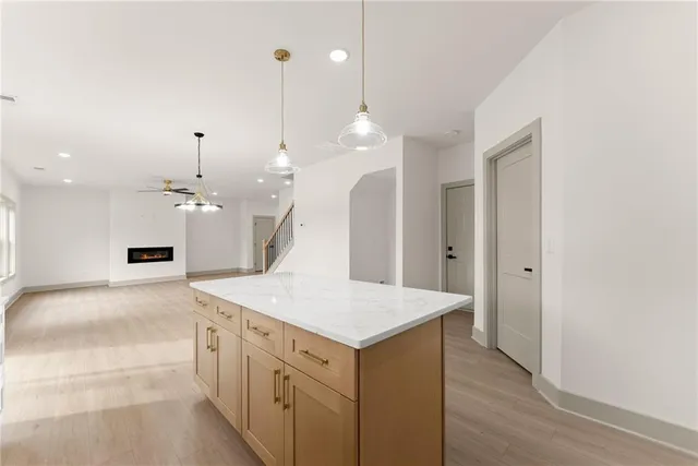 a large kitchen with a sink a center island a wooden floor and a chandelier
