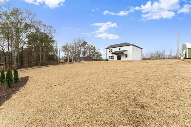 a view of house with yard and trees in the background
