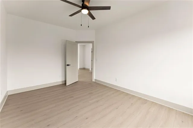 an empty room with wooden floor fan and windows