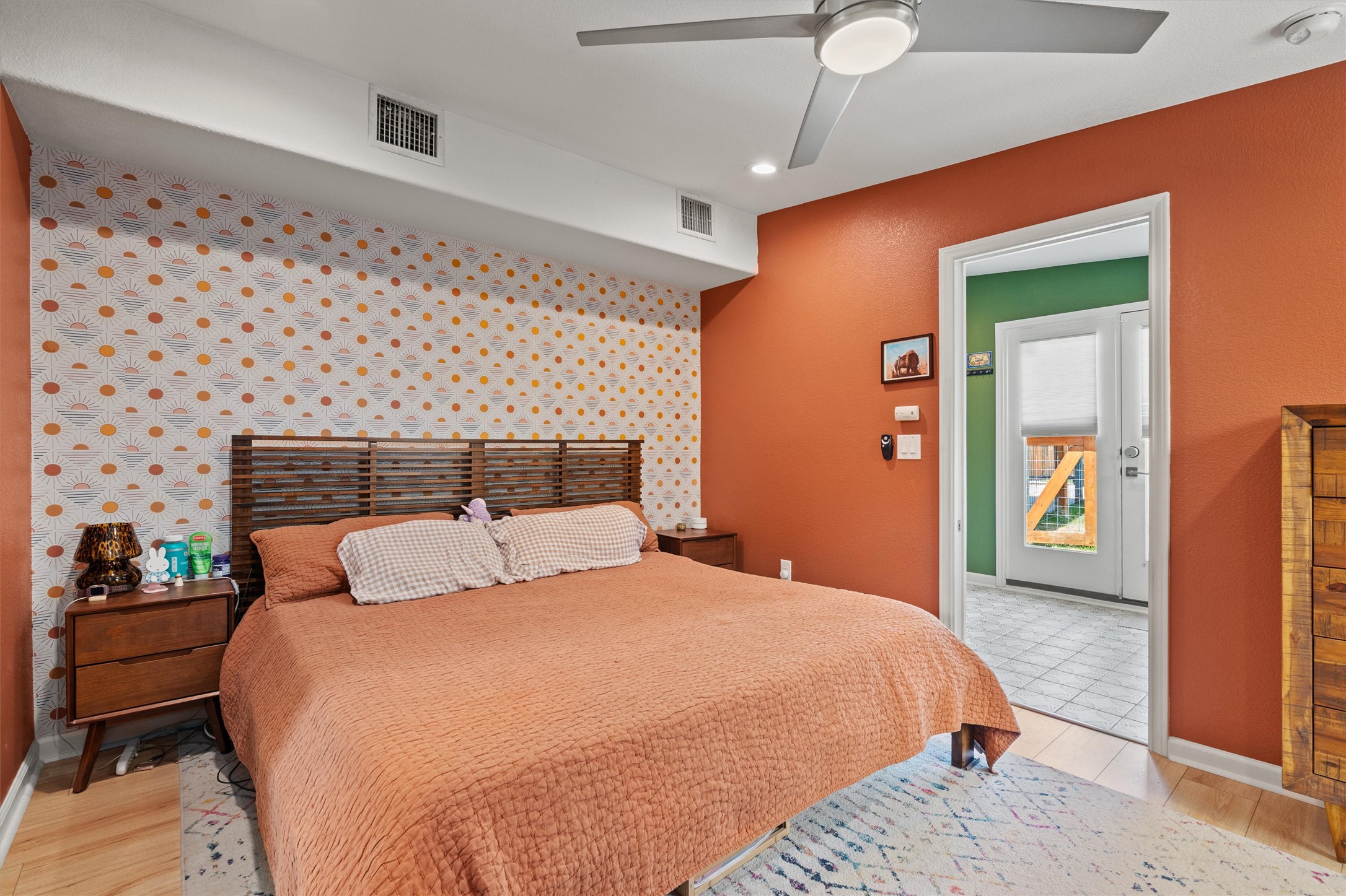 1147 Webberville Road Austin, TX 78721 - Photo 21 of 37 A vibrant bedroom offers a comfortable retreat with sleek hardwood floors and a door leading to an outdoor space.