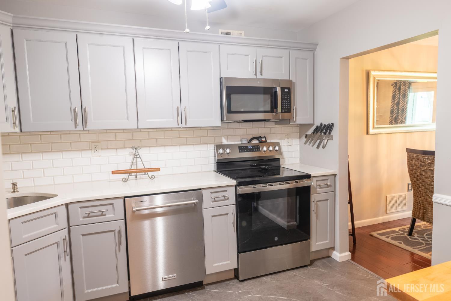 13 Mine Road Jamesburg, NJ 08831 - Photo 15 of 52 a kitchen with white cabinets and stainless steel appliances