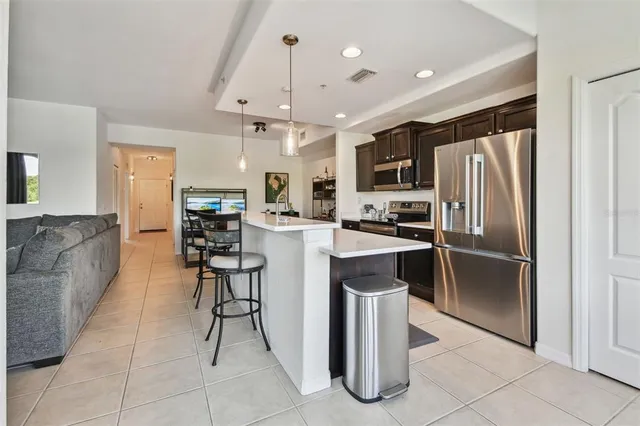 a kitchen with stainless steel appliances kitchen island granite countertop a refrigerator a stove a sink a oven and a dining table with wooden floor