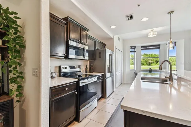 a kitchen with stainless steel appliances granite countertop a refrigerator a sink and a stove