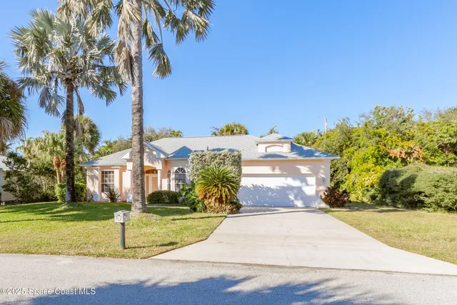 a view of a white house with a yard and palm trees