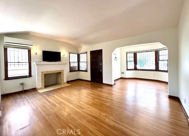 an empty room with windows fireplace and wooden floor