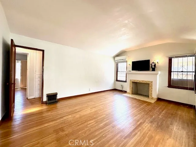 a view of an empty room with wooden floor and a fireplace