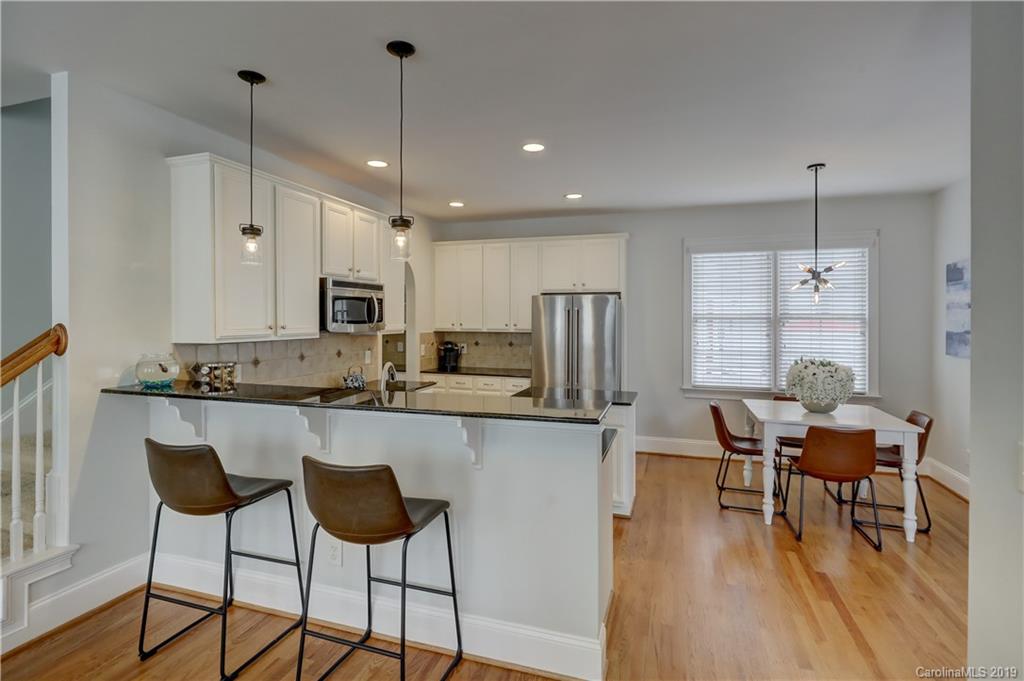 170 Mills Lane, Unit 761 Fort Mill, SC 29708 - Photo 9 of 35 a kitchen with stainless steel appliances kitchen island granite countertop a dining table chairs and white cabinets