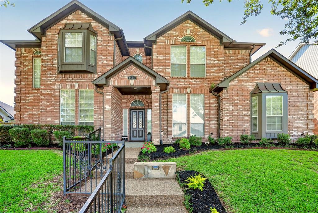 4509 Scenic Drive Rowlett, TX 75088 - Photo 39 of 40 Brick exterior home featuring a covered entry, decorative front door, multiple bay windows, arched window accents, and manicured landscaping