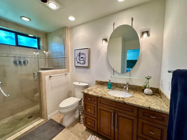 a spacious bathroom with a granite countertop toilet a sink and a mirror