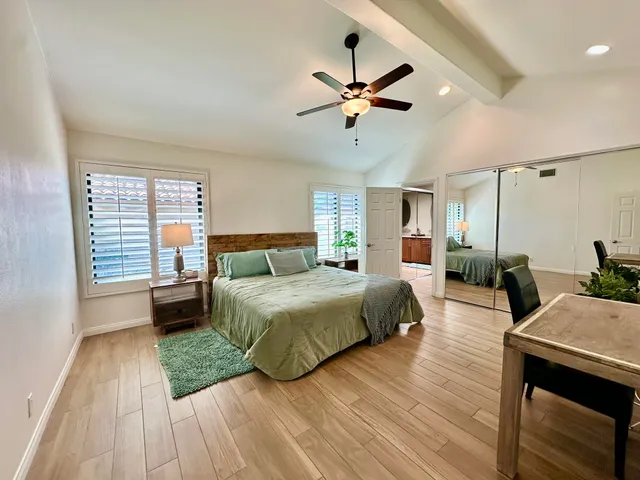 a spacious bedroom with a bed a chandelier and a dresser
