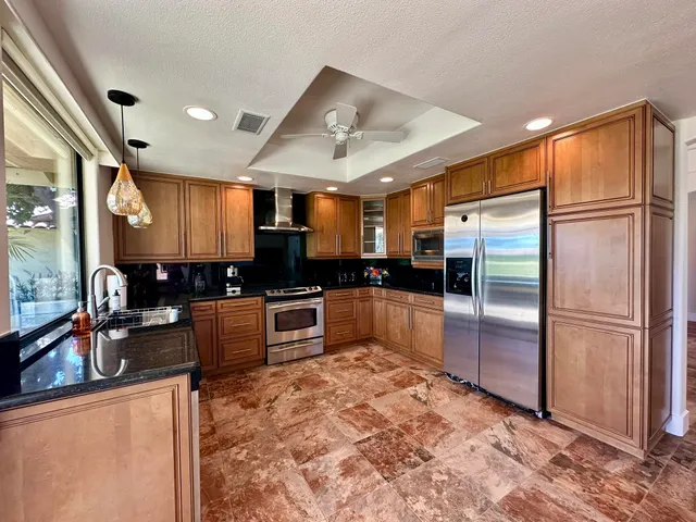 a kitchen with granite countertop a refrigerator and a stove top oven