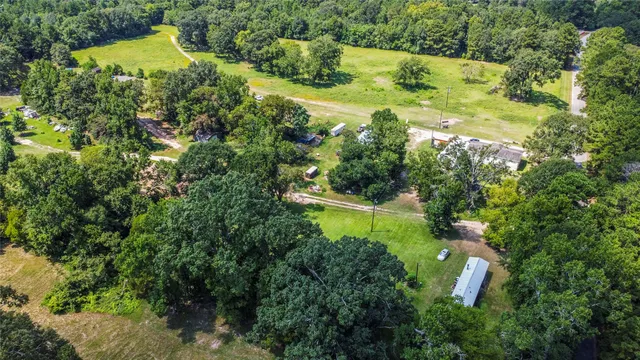 an aerial view of residential house with outdoor space and trees all around