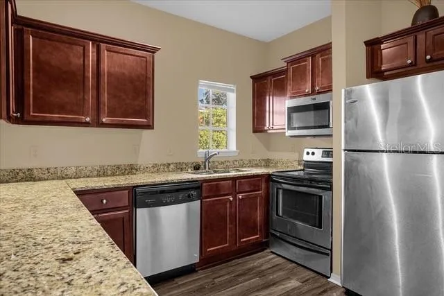 a kitchen with stainless steel appliances granite countertop a refrigerator and a stove top oven