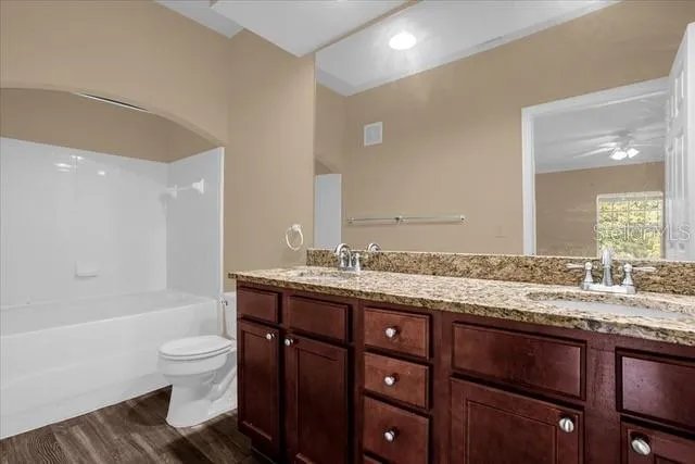 a bathroom with a granite countertop toilet a sink and a bathtub