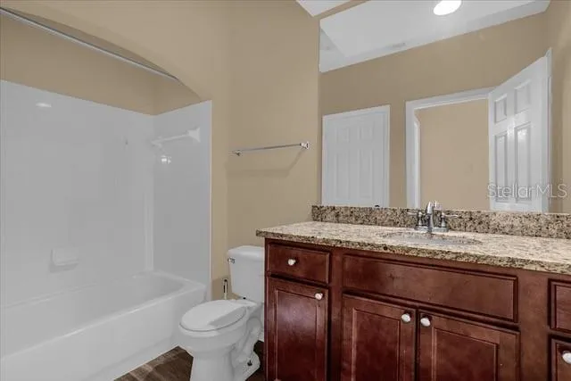 a bathroom with a granite countertop toilet sink and mirror